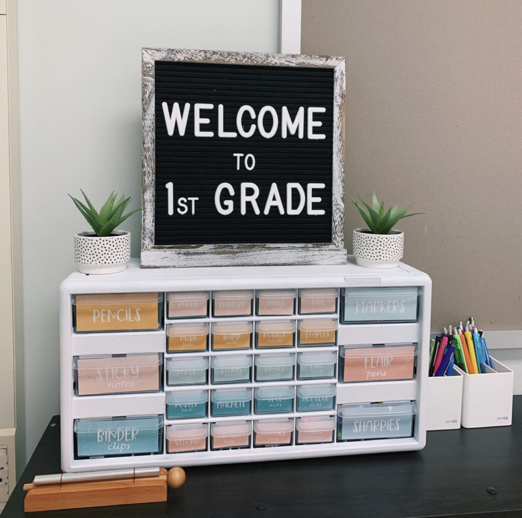 This image is a picture of a white teacher toolbox decorated with calm color labels. The labels read different things like "sharpies, tape, rubber bands, flair pens, highlighters" and more. The larger & smaller labels are all solid colors. 