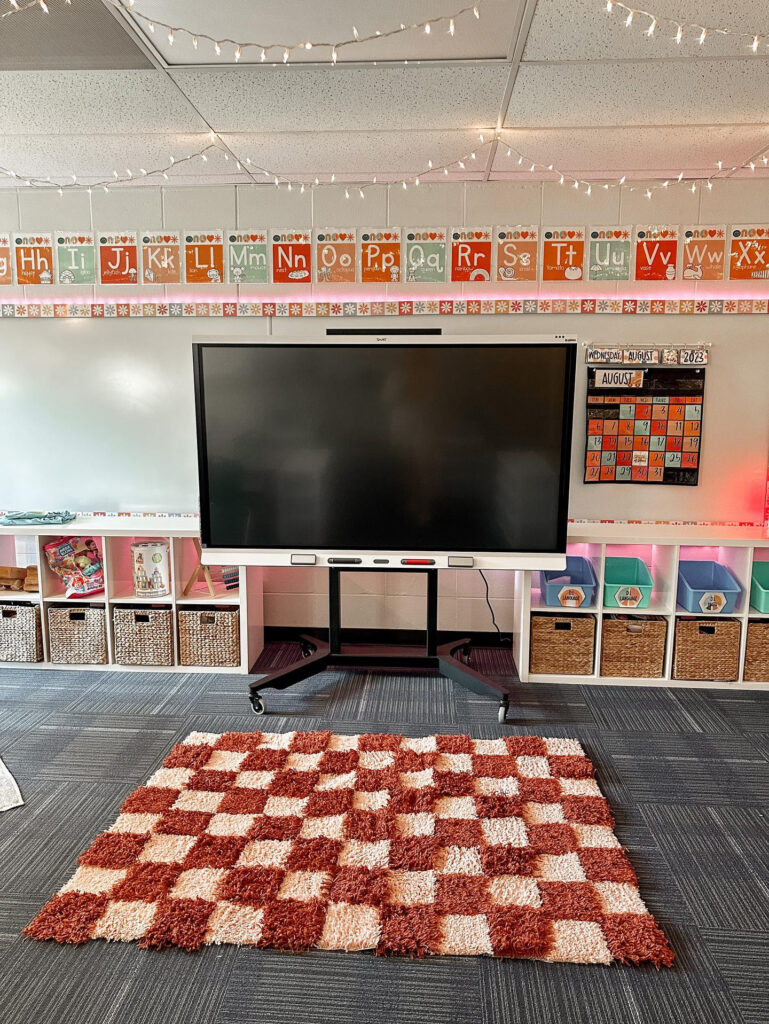 This image shows the front of a classroom decorated with the groovy classroom theme. There is a great shag rug at the front of the room and lots of twinkle lights along the top.