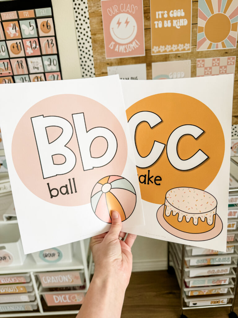This image shows two alphabet posters with the letter, word, and clipart in front of the pastel retro classroom decor theme.