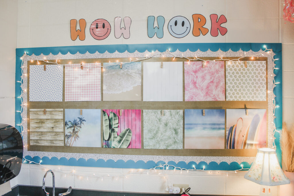 This image shows a Wow Work display where student work is hung throughout the year. It is surrounded by twinkle lights and has fun, beach-themed scrapbook pages as place holders. 