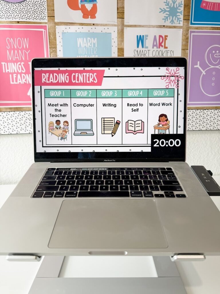 This image shows a centers slide with 5 different group activities listed an a 20 minute timer in the bottom corner. Each group's section has the words for the task and a small image.