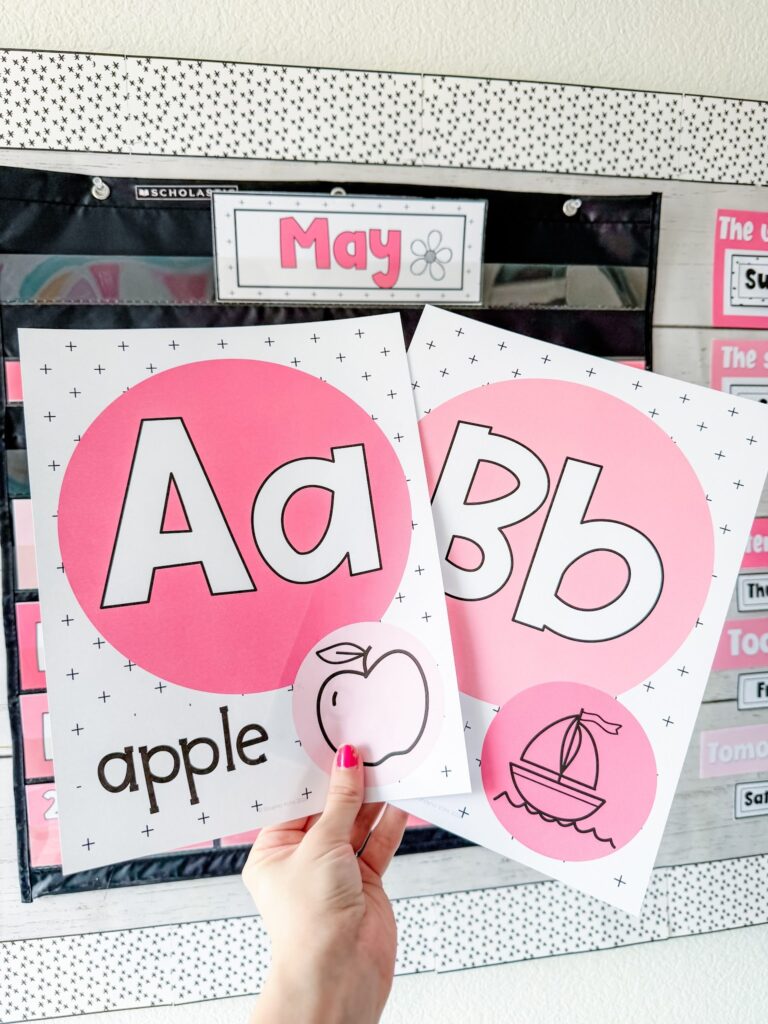 This image shows a fun font primary version of the alphabet posters included in the simple + pink classroom decor theme. Each poster has the uppercase and lowercase letter, a word that goes with the sound, and an image of that word. 