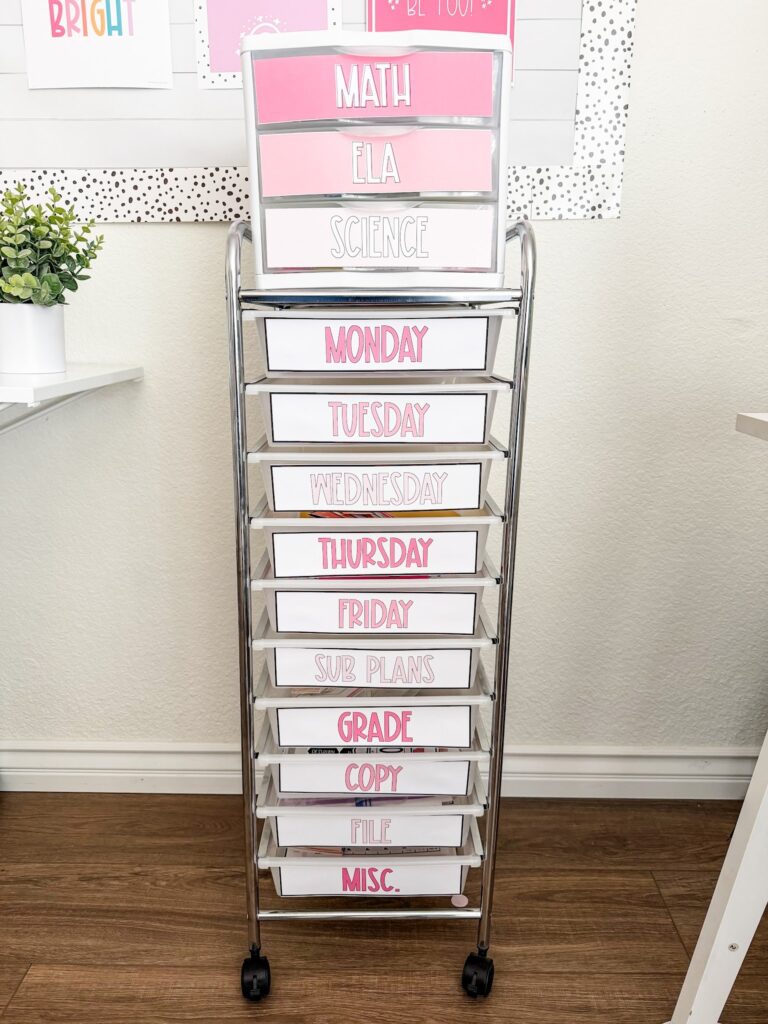 This image shows a 10 drawer cart with a Sterilite three drawer bin on top of it. Both items have labels on the drawers indicating what is inside. The labels for the 10 drawer cart have a white background and pink colored letters. The labels for the Sterilite 3 drawer bin are solid pink with white letters. 