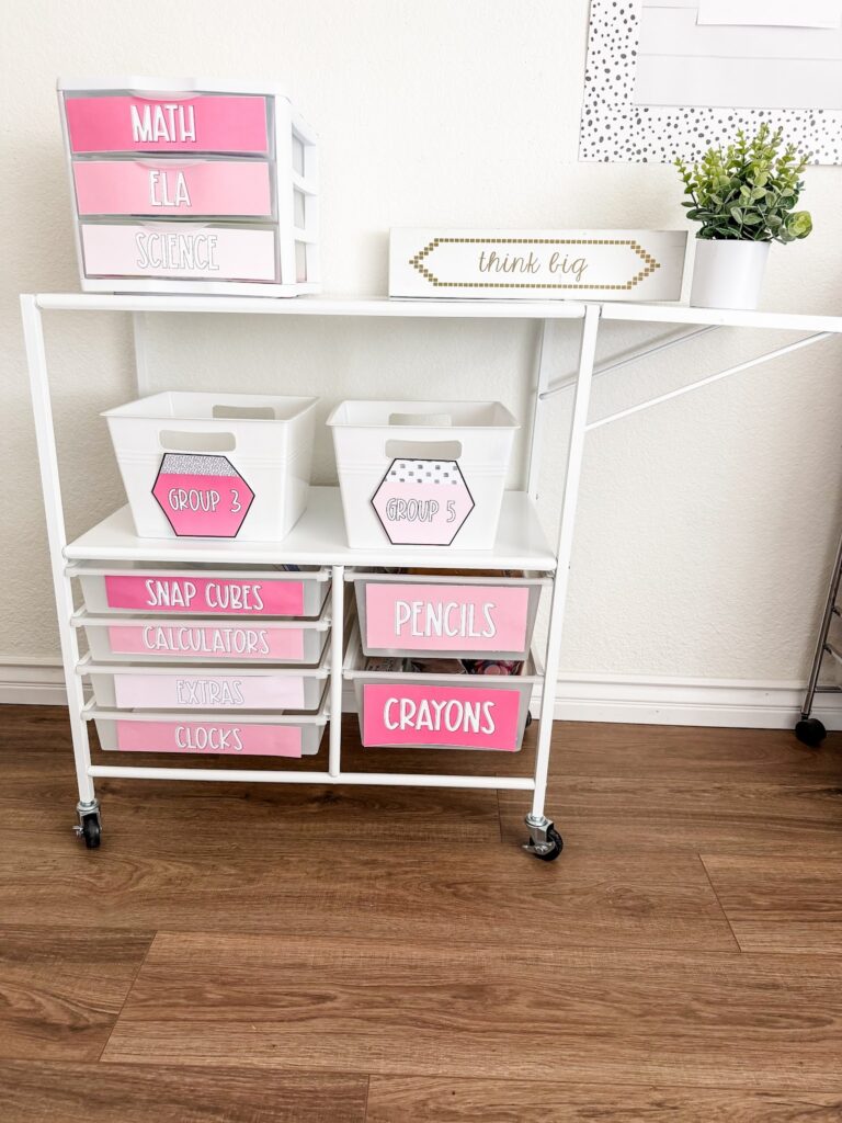 This image shows a rolling cart with a Sterilite three drawer bin on top of it. Both items have solid pink labels on the drawers indicating what is inside. 