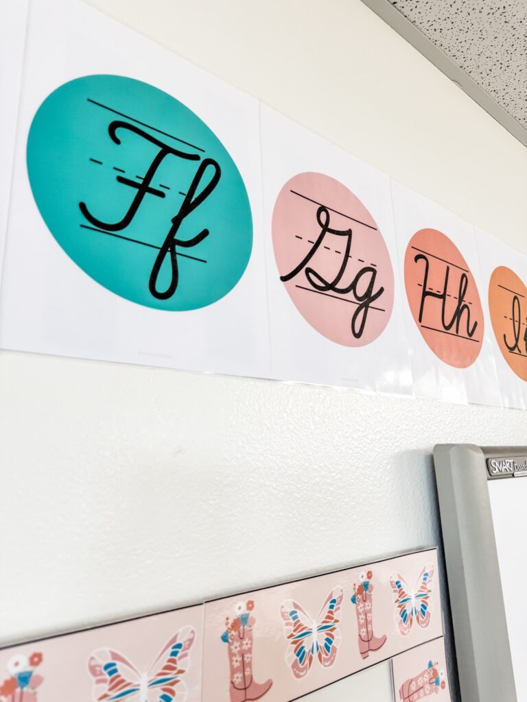 This image show the cursive alphabet line hanging above the whiteboard using the painter's tape and hot glue method.