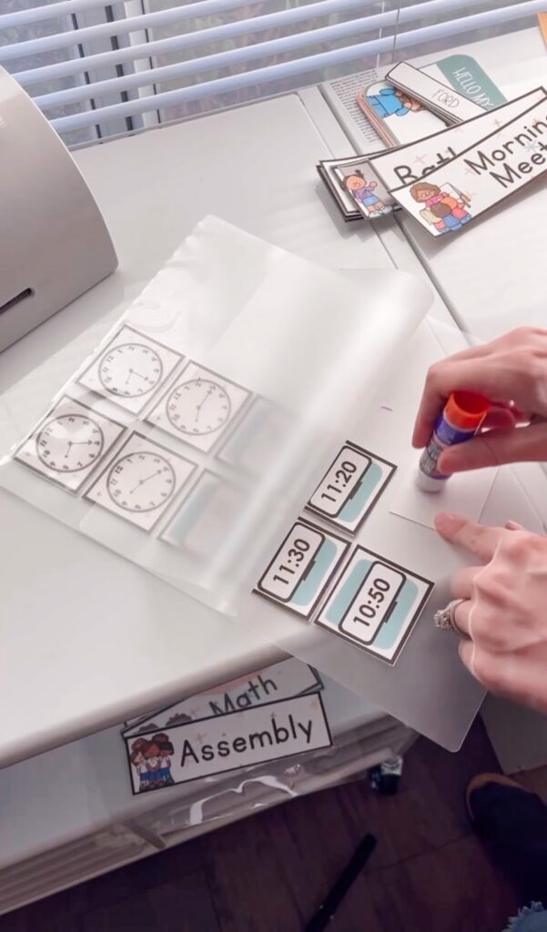 This image shows a teacher using a glue stick to glue down small pieces she wants to laminate from her classroom decor before sending them through the laminator.