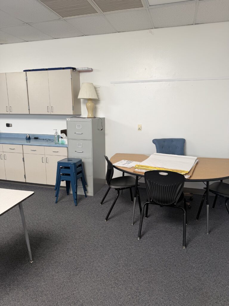 This image shows the side of a classroom with a small group table on one end and some cabinets along the wall.