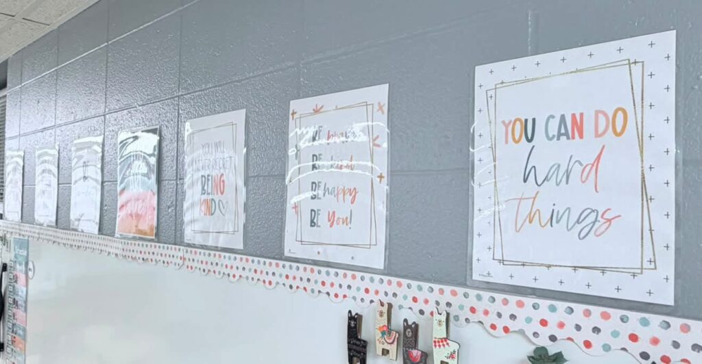 This image shows inspirational posters hanging over the front whiteboard of a classroom. 
