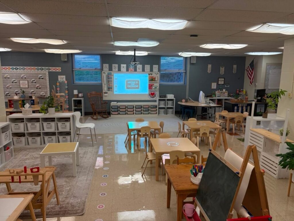 This image shows an overview of a pk classroom setup with small tables, a play corner, and a larger area in the front of the classroom.