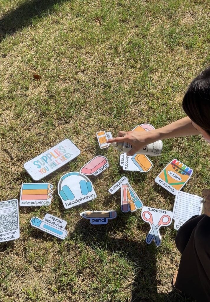 This image shows a teacher actively spraying the Matte Clear spray on top of the display pieces outside on the grass.